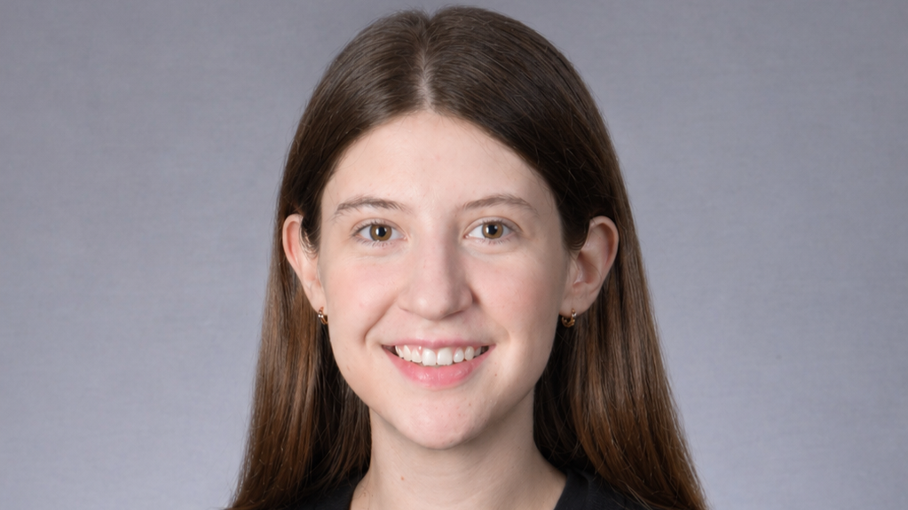 Isabella Grion wears a black shirt while smiling in front of a gray background. Isabella Grion wears a black shirt while smiling in front of a gray background.